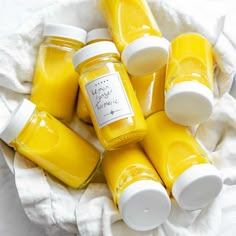 five jars of yellow liquid sitting on top of a white cloth next to each other