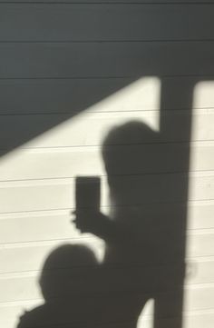 the shadow of a person holding a cup