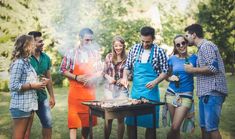 a group of people standing around a bbq grill