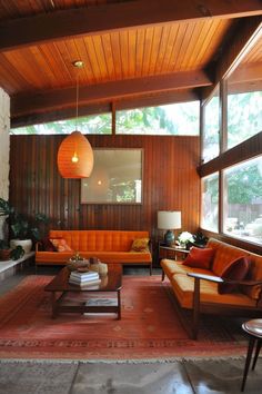 a living room filled with lots of furniture and large windows on top of the ceiling