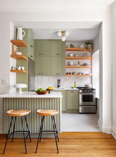 two stools sit in front of the kitchen island with open shelving above it