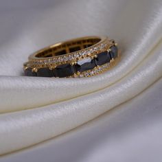 a black diamond ring sitting on top of a white cloth