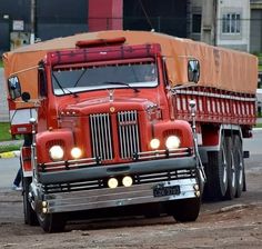 a large red truck driving down a dirt road