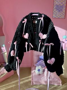 a black jacket with pink hearts hanging from it's back and on display in front of a mirror