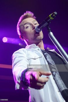 a man in white shirt holding a microphone on stage