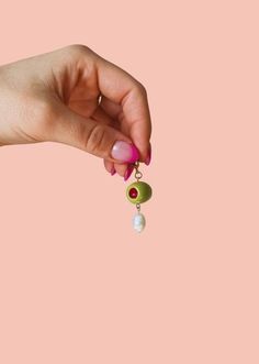 a woman's hand holding a pair of earrings with pearls hanging from the end