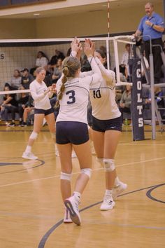 two girls playing volleyball on a court with people watching