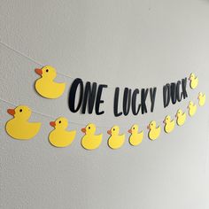 one lucky duck banner with rubber ducks hanging on the wall next to it is a sign that says,'one lucky duck '