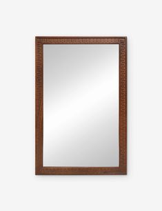 a wooden mirror hanging on the wall next to a white wall with a brown frame