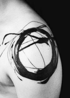 a black and white photo of a man's shoulder with a circle tattoo on it