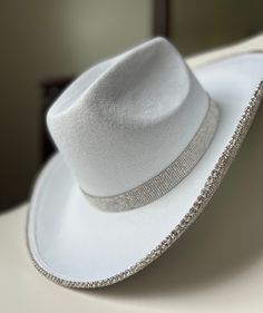 "This custom made white cowboy hat is lined with rhinestones under the hat rim and around hat base.  22\" around inside of hat Items are hand made so you may find some subtle imperfections. Hat may have some residual glue smell, this will fade after a week or so. PLEASE MESSAGE ME FOR ANY QUESTIONS OR SPECIAL REQUESTS!" White Fedora For Rodeo And Kentucky Derby, White Western Fedora For Kentucky Derby, White Wide Brim Top Hat In Western Style, White Flat Brim Fedora For Western-themed Events, White Country Top Hat With Curved Brim, White Brimmed Country Style Top Hat, White Brimmed Country Top Hat, White Country Style Top Hat With Curved Brim, Country Style White Brimmed Top Hat