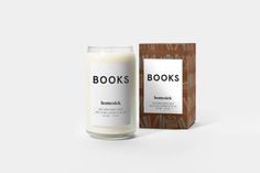 a candle that is next to a box with books on it and the words homesick written in black