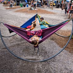 two people laying in hammocks on the ground