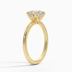 a yellow gold engagement ring with three stones on the top and bottom, set against a white background