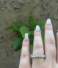 a woman's hand with a wedding ring on it and a green plant in the background