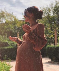 a woman in a brown dress is holding her hands together