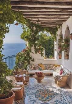 an outdoor patio with potted plants and flowers on the table, overlooking the ocean