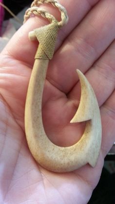 a hand holding a small wooden hook with an arrow on it's end, in the palm of someone's hand