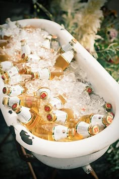 a tub filled with lots of bottles of beer sitting on top of a wooden table