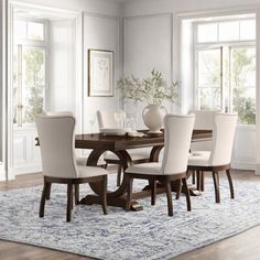 a dining room table with white chairs and an area rug in front of the window