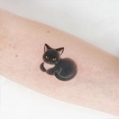 a black cat with yellow eyes sitting on the arm