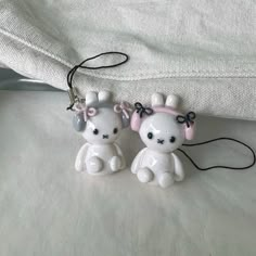 two little white teddy bears sitting next to each other on top of a bed together