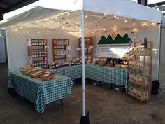 an outdoor market with several tables covered in blue and white checkered cloths