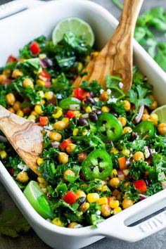 a white casserole dish filled with corn, green peppers and cilantro