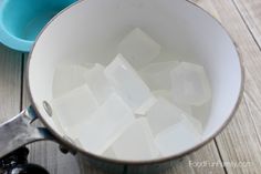 ice cubes are in a pot on the table next to a blue bowl and spoon