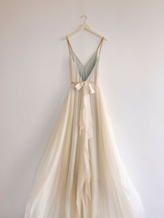 a dress hanging up against a wall with a hanger in front of the dress