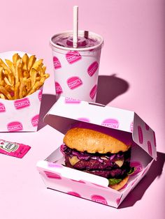 a hamburger and french fries are sitting next to each other on a pink tablecloth