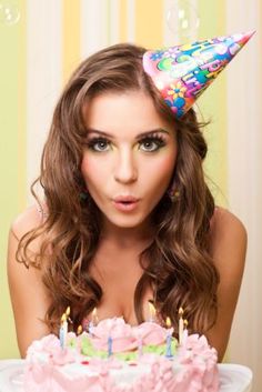 a woman wearing a party hat with candles on her head and birthday cake in front of her