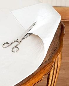 a pair of scissors sitting on top of a table with white napkins under it