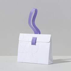 a white paper bag with a purple ribbon hanging from it