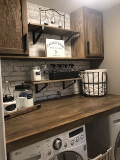 a washer and dryer in a room with wooden shelves on the wall above them