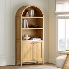 a wooden book shelf with books on it in front of a white wall and window