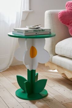 a small table with books on it in the middle of a wooden floor next to a couch