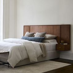 a bed with white linens and pillows in a bedroom next to a large window