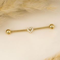 a gold heart shaped barbell ring with two balls and a diamond in the middle