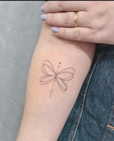 a woman's arm with a small dragonfly tattoo on the left inner arm