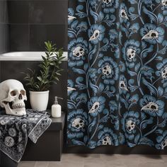 a bathroom with a skull on the floor next to a shower curtain that has blue flowers and skulls on it