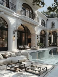 a large white house with a pool and lounge chairs in front of the home's outdoor living area