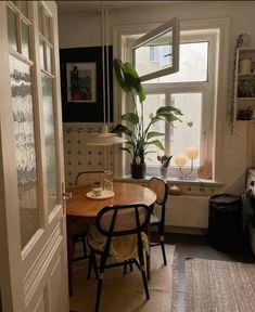 a dining room table with two chairs and a potted plant in the window sill