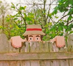 a wooden fence with two hand puppets on it