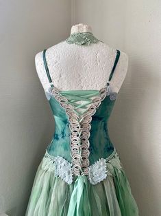 a green and white corset with lace on the top, attached to a mannequin