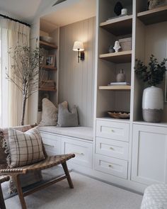 a living room with white furniture and shelves filled with vases, plants and other items