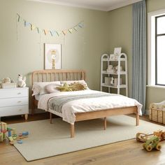 a child's bedroom with green walls and white furniture, including a wooden bed