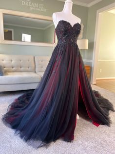 a black and red dress on display in front of a couch with a mirror behind it