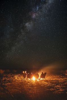 people sitting around a campfire under the night sky