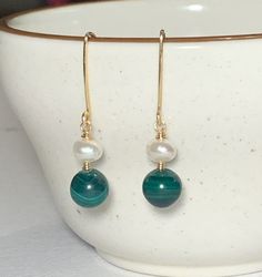 These handmade beautiful Malachite and Fresh water Pearl earrings look pretty, the combo of grass green and white match well together. Amazing Malachite is amazing gemstone which traditionally used to ward of danger and illness, the deep green  is soothing & merge well beautiful with white Pearl. Genuine Malachite gemstone bead & Fresh Water Pearl is wrapped with gold tone wire. The full drop of the earrings is approximately 1.5 inches. Genuine Malachite Fresh Water Pearl Gold tone Wire Handmade Green Hand Wrapped Earrings As Gift, Green Hand Wrapped Earrings For Gift, Hand Wrapped Green Earrings For Gifts, Gift Green 14k Gold Filled Earrings, Green 14k Gold Filled Earrings With Ear Wire, Green Dangle Pearl Earrings With Ear Wire, Green Wire Wrapped Round Earrings, Handmade Green 14k Gold Filled Earrings, Green Wire Wrapped Drop Earrings